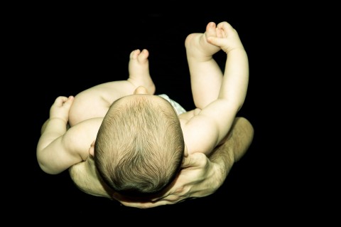 sesión de fotos de recien nacido, padre agarra entre sus brazos a su hijo