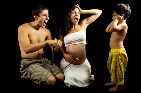 Familia jugando con su hijo mayor en sesión de embarazo