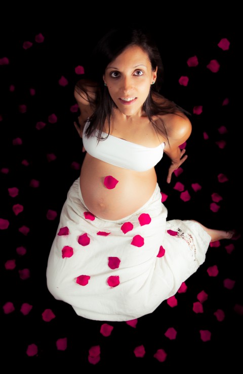 Sesión de embarazo, madre con pétalos de rosas